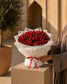 Woman in abaya holding a lush red tulip bouquet in white wrap with red ribbon - Tulip Wonderland by AIWA Flowers