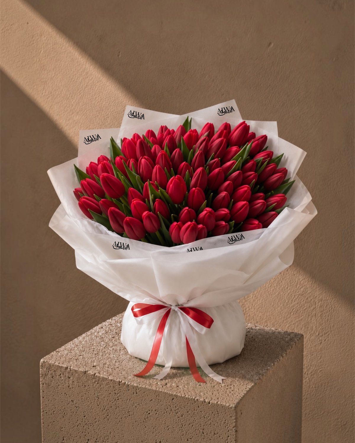 Full studio shot of a red tulip bouquet in white wrap with red and white ribbon - Tulip Wonderland by AIWA Flowers