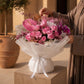 woman holding pink rose, orchid and hydrangea bouquet with gold accents in white wrap – Versailles Garden by AIWA Flowers