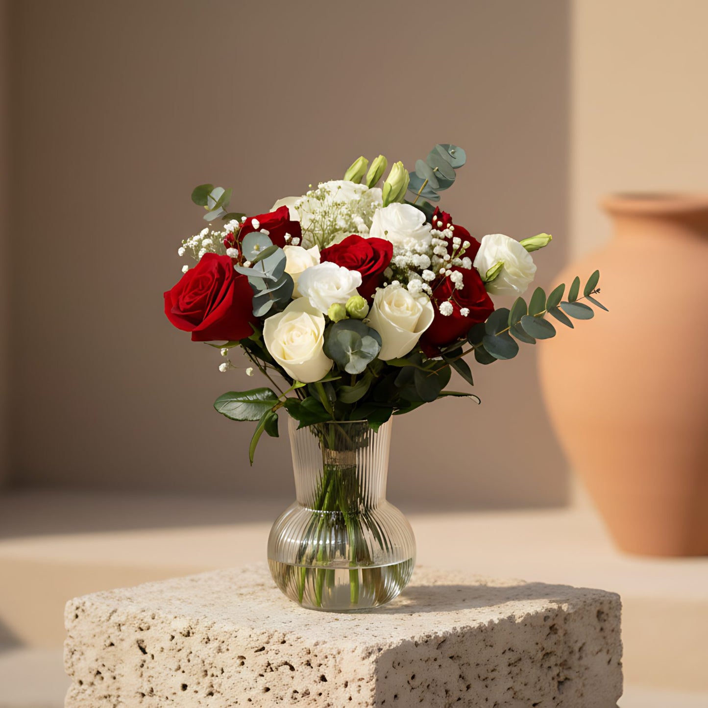 Victoria arrangement with white and red roses, lisianthus, gypsophila and eucalyptus in a clear glass vase