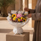 Woman holding a bright pink hydrangea and sunflower bouquet in white wrap - Ultra by AIWA Flowers