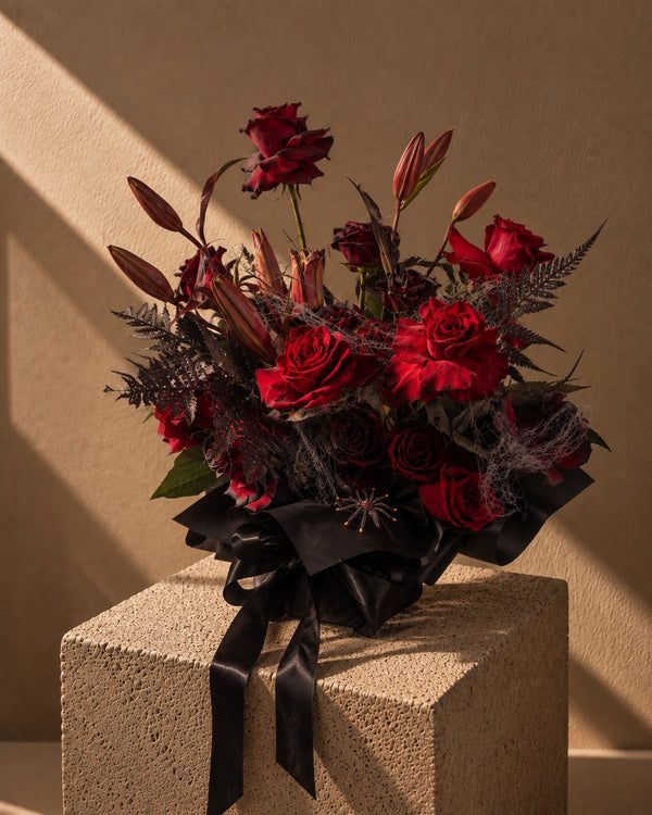 Wicked Blooms Halloween bouquet of red roses and lilies with black fern and spider web in black wrapping