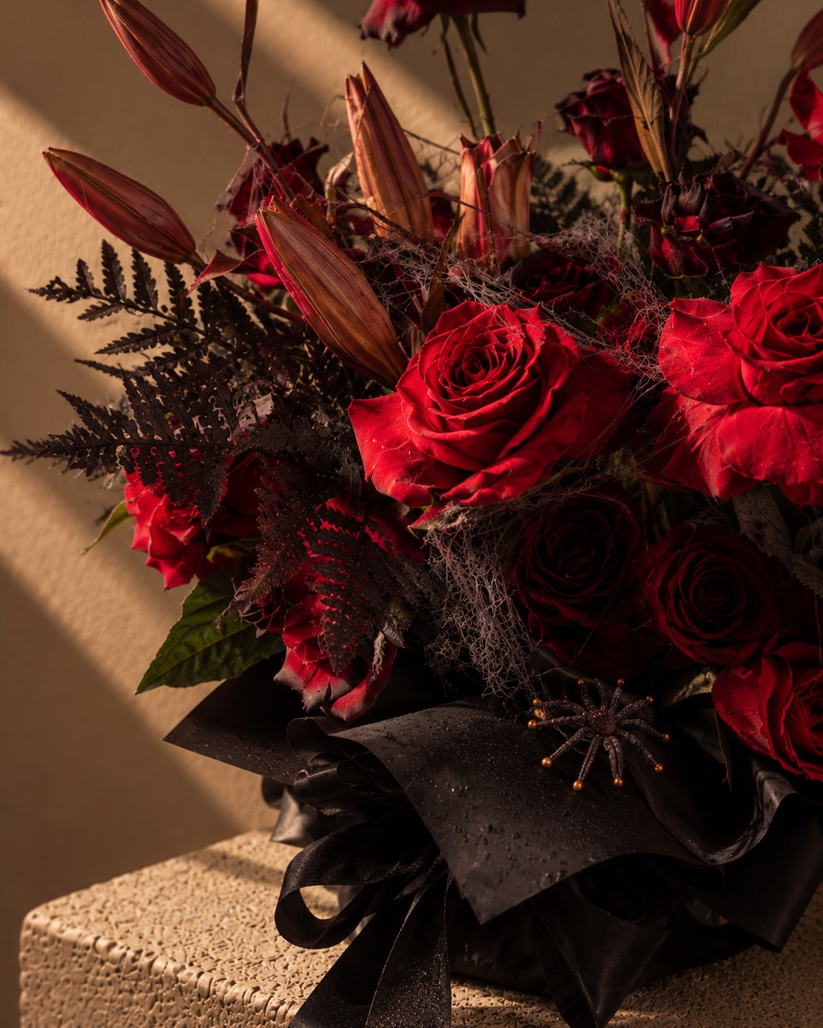Close-up of red roses, black fern and spider accent in Wicked Blooms