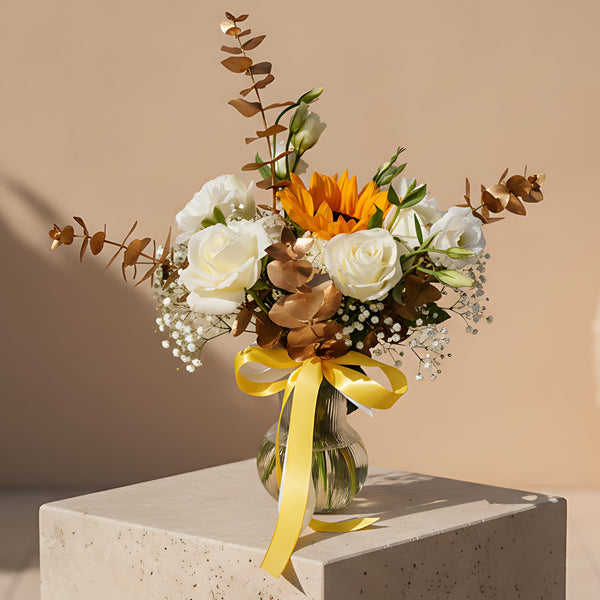 Zakat arrangement with white roses, sunflower, carnations and lisianthus in a clear glass vase