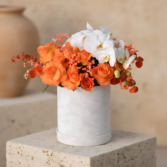 Zinnia flower box with orange roses, orchid stem, orange gypsophila and eucalyptus in a white velvet box